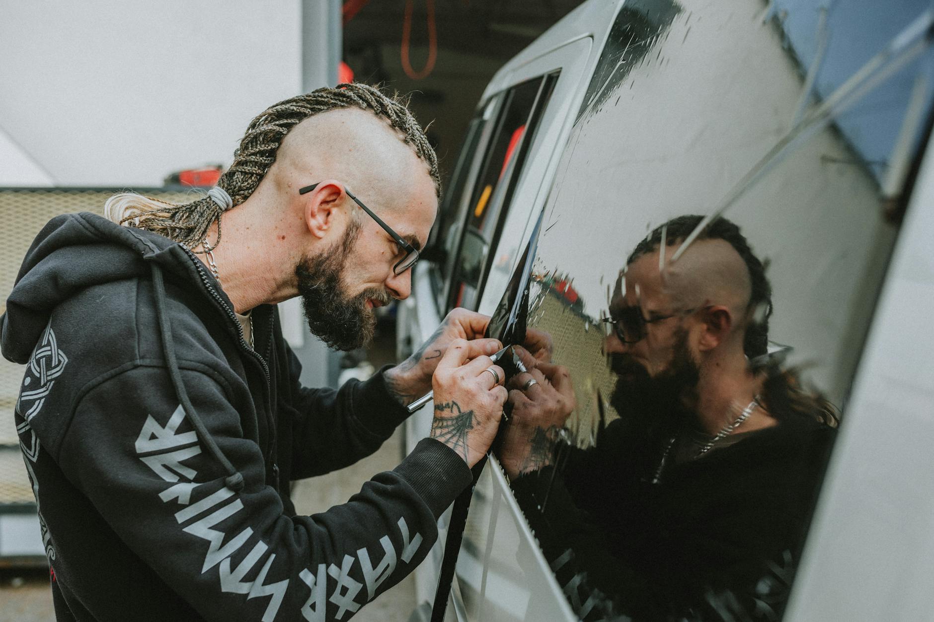 man with dreadlocks working by car window