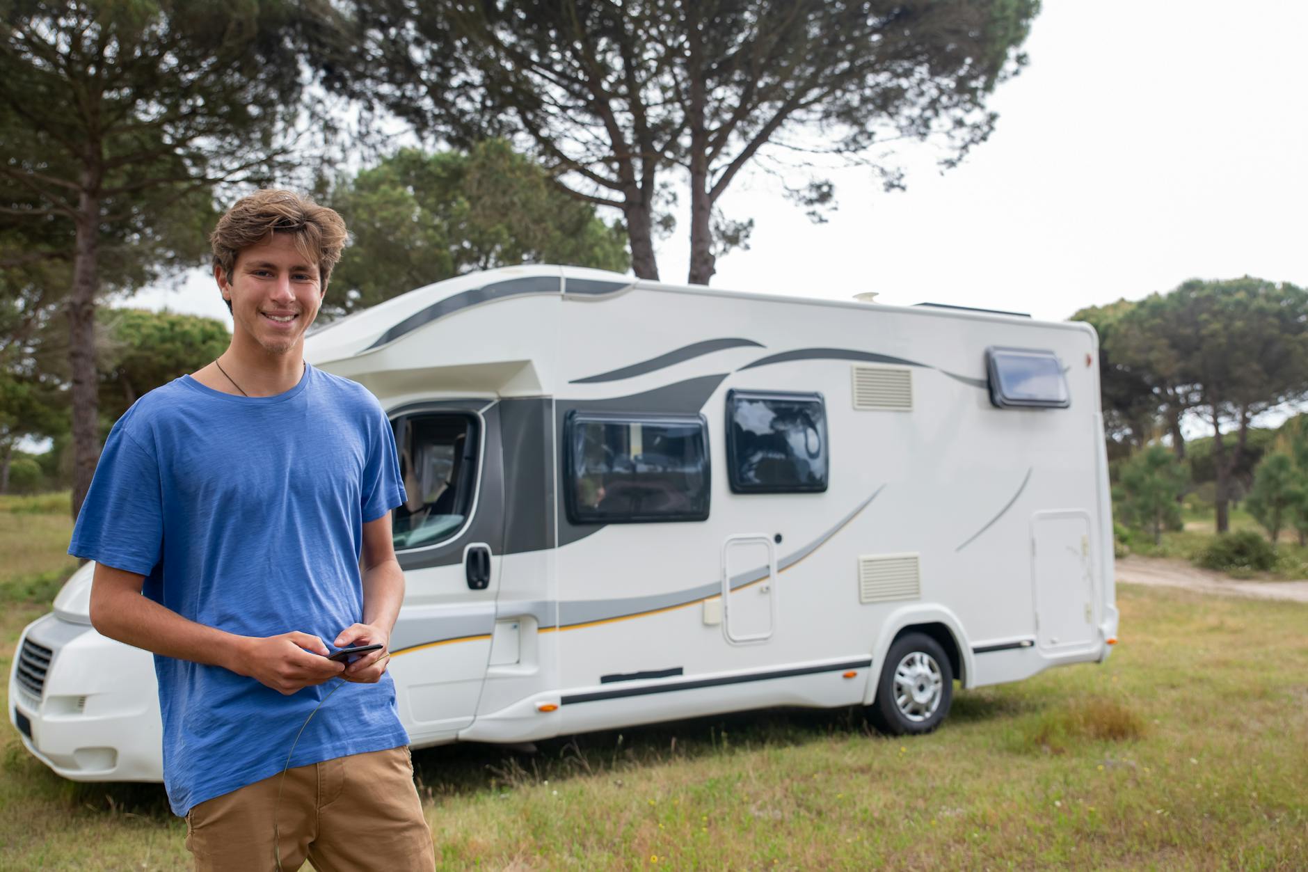 man in blue t shirt standing by a white camper van