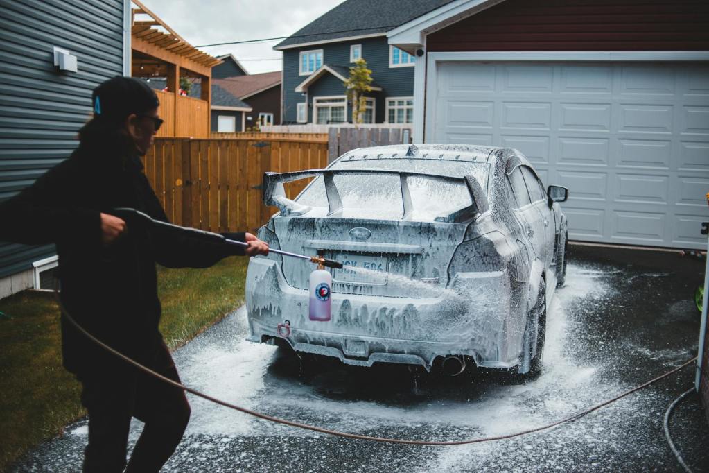 unrecognizable worker washing luxury car