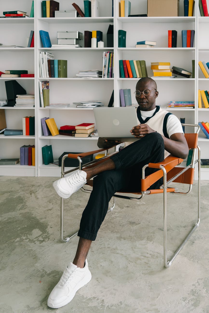 a man sitting on an armchair while using a laptop